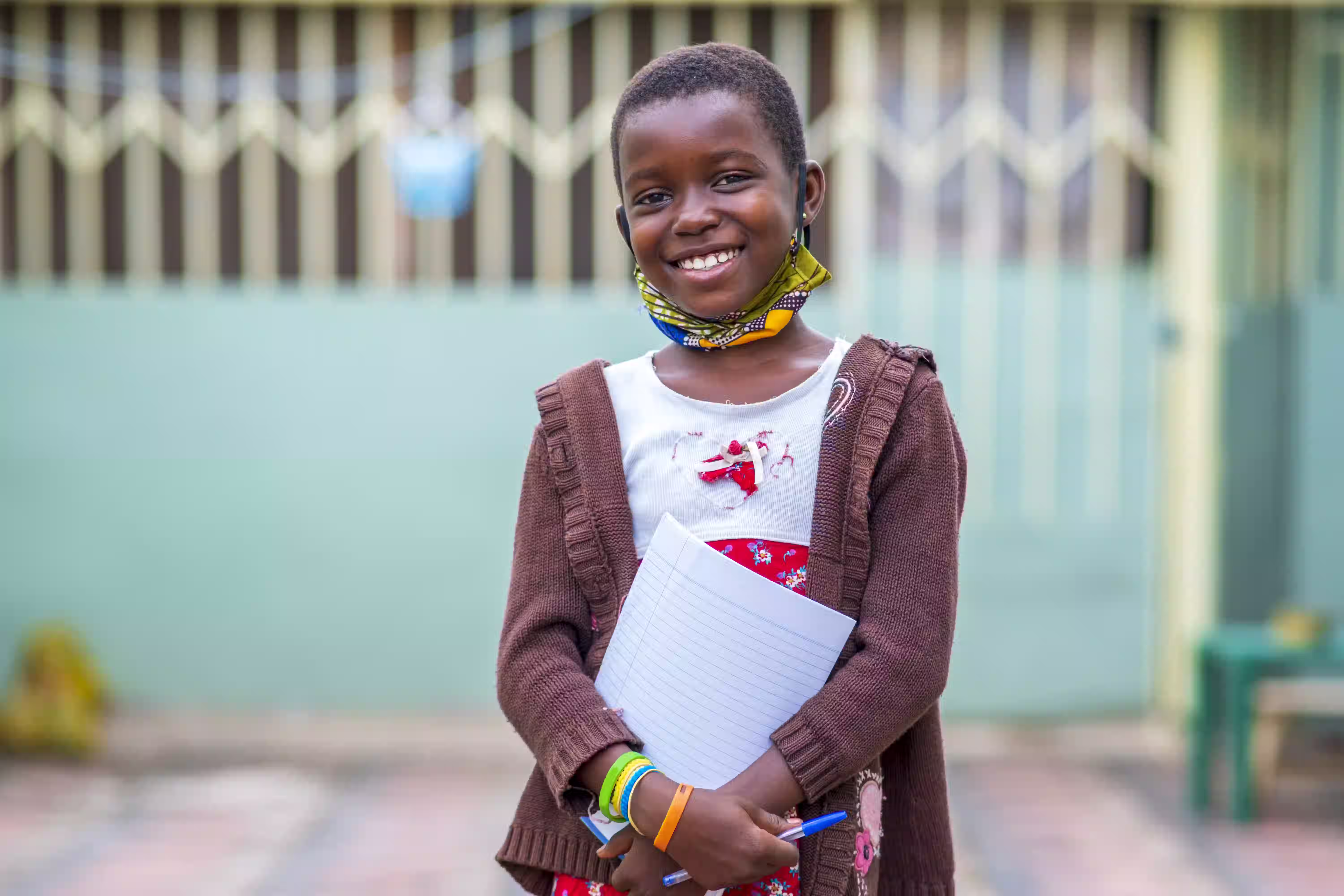 A child holding a notebook, supported by MIWA's education programme